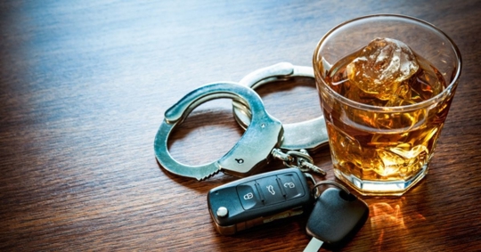 Car keys and handcuffs near an alcoholic drink
