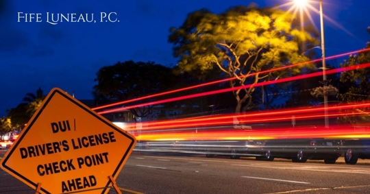 DUI / Driver license checkpoint sign with deep blue sky and car light trains in background
